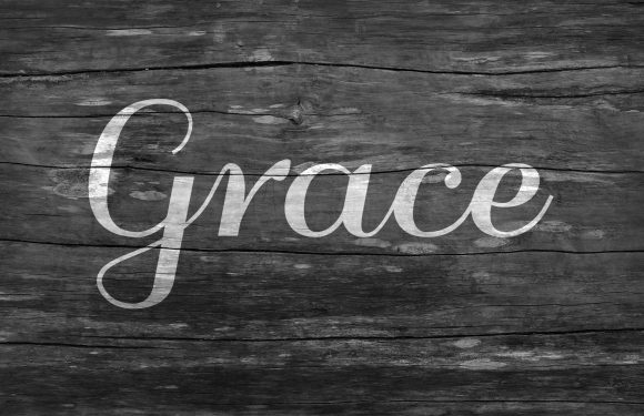 The word "Grace" written in cursive on a weathered wooden background.