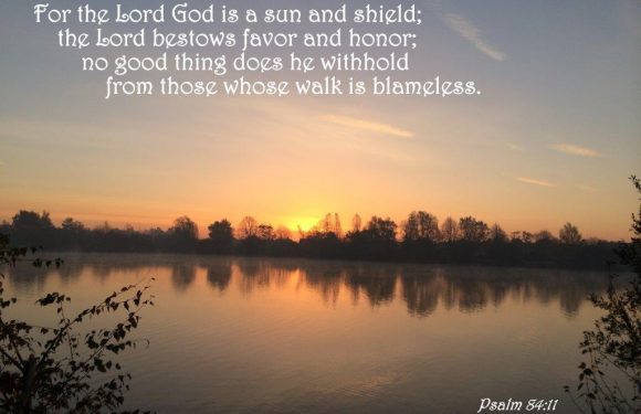 A serene lakeside scene at sunrise with trees along the horizon, calm water reflecting the sky, and a Bible verse from Psalm 84:11 overlaid.