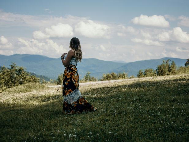 Woman looking over a prairie at sunset