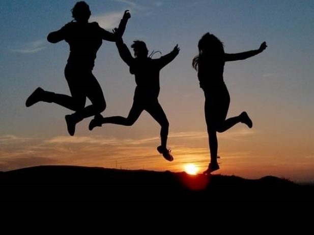 Silhouette of people jumping in front of a sunset