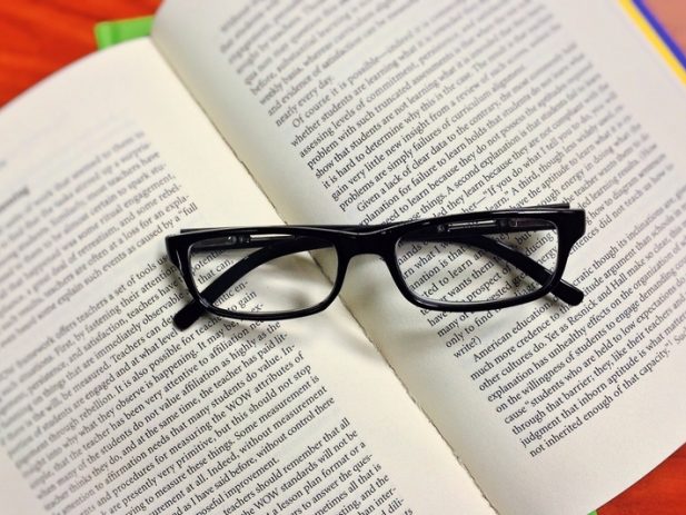 Open book with folded glasses on top