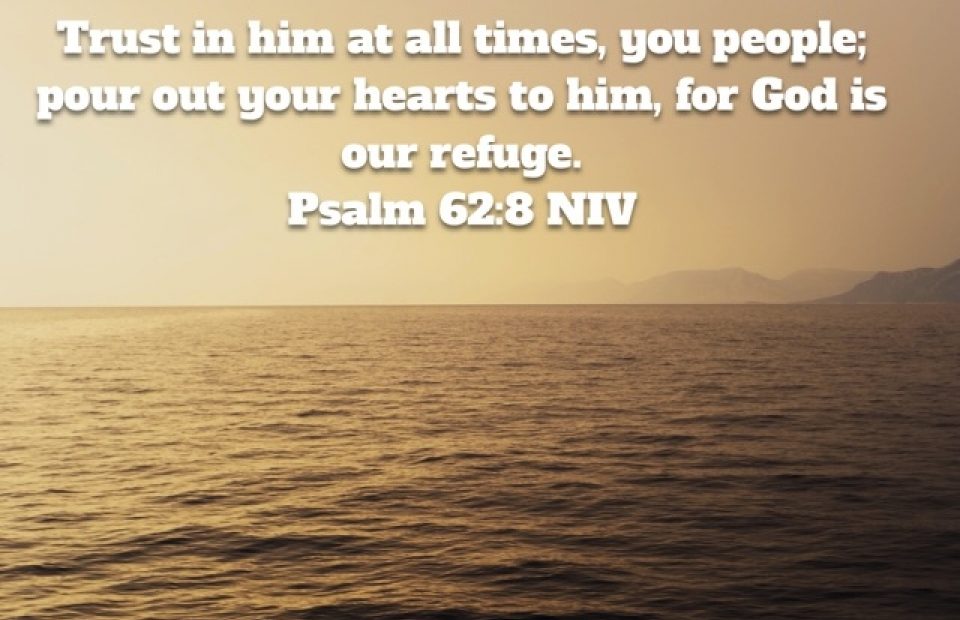 A peaceful ocean scene at sunset with mountains in the background, overlaid with a Bible verse from Psalm 62:8 NIV about trusting God.