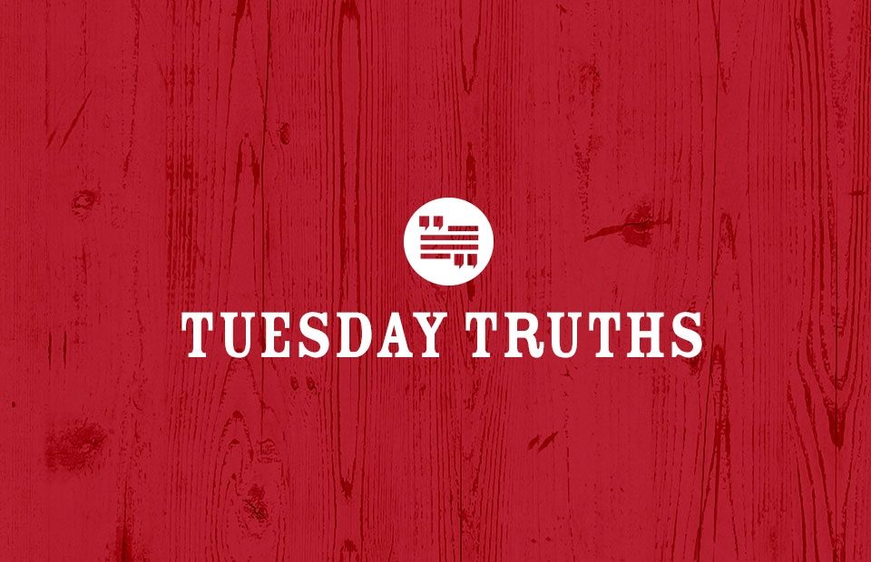 Red wooden background with white text that says "Tuesday Truths" and a circular logo above the text.