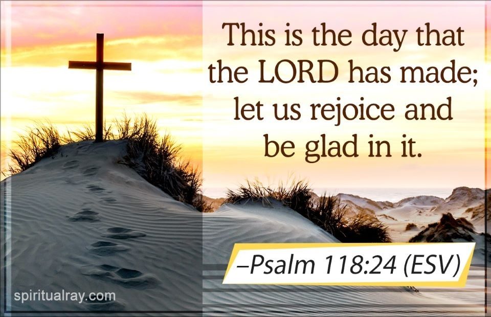 A cross stands on a sand dune at sunset, with a quote from Psalm 118:24 (ESV) about rejoicing in the day the Lord has made, with a beach and dunes in the background.